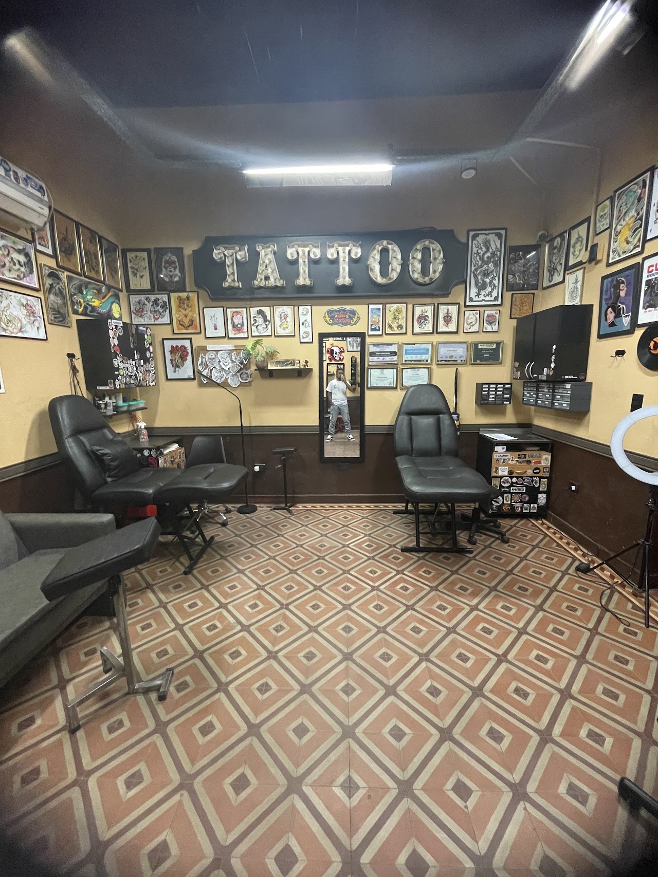 Interior del estudio Walterink Tattoos con pared de flash art y cartel luminoso TATTOO